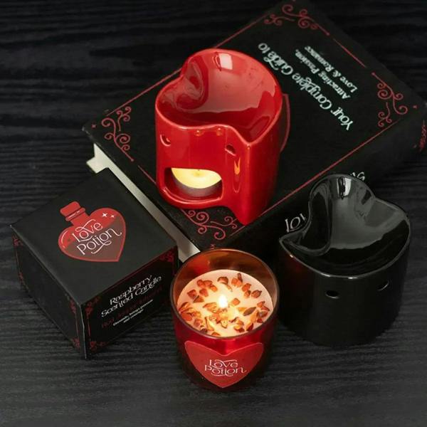 Red heart oil burner with glowing tealight in open front, on dark base