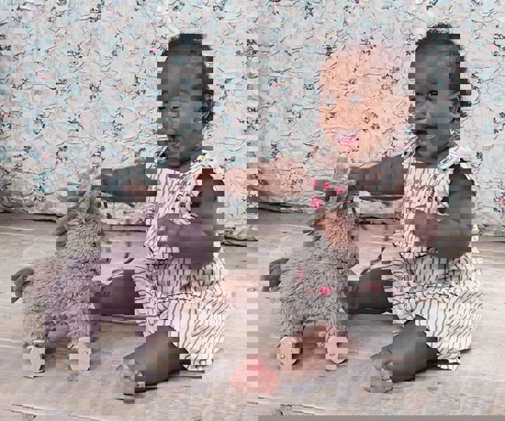 Toddler girl playing with Norbert Donkey Pull Along Toy with wooden wheels