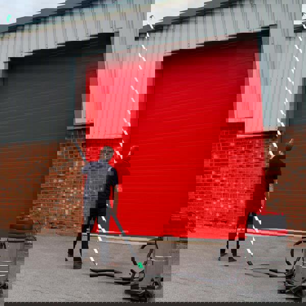 80L wet and dry vacuum with gutter vacuum poles and 5m hose, shown in use against a red garage door, highlighting its versatility