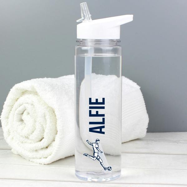 A transparent 750ml sports water bottle custom-printed with the name 'Alfie' in deep navy blue vertical font above a male football player graphic kicking a ball, with a rolled white towel behind it.