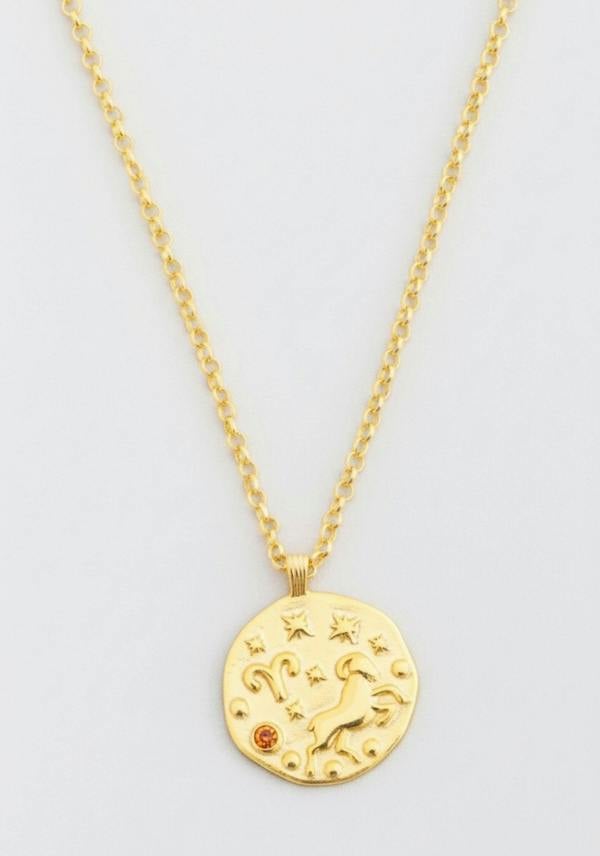 Gold necklace with a celestial pendant on a light gray background