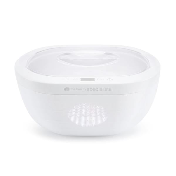 The Rio Paraffin Wax Heater is a white, oval-shaped device with a transparent lid, small digital display, and subtle branding, designed for comfort and skin hydration. Shown against a plain white background.