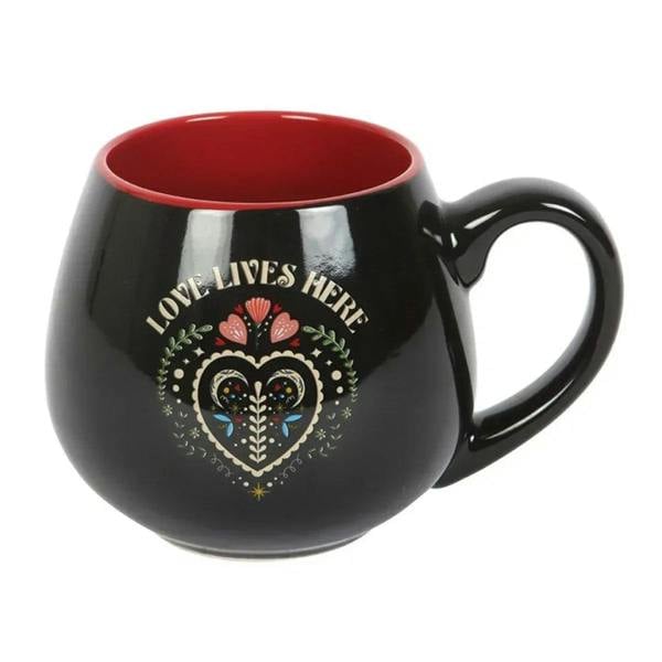 Black ceramic mug with red interior, LOVE LIVES HERE folk heart graphic, and handle