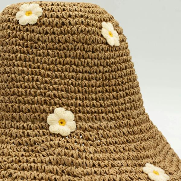 Close-up of woven straw hat with white daisy appliques on a tan crown
