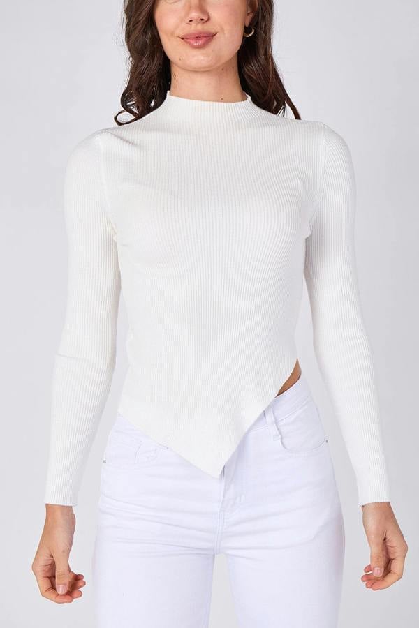 Person wearing a white ribbed sweater and light purple pants on a plain background