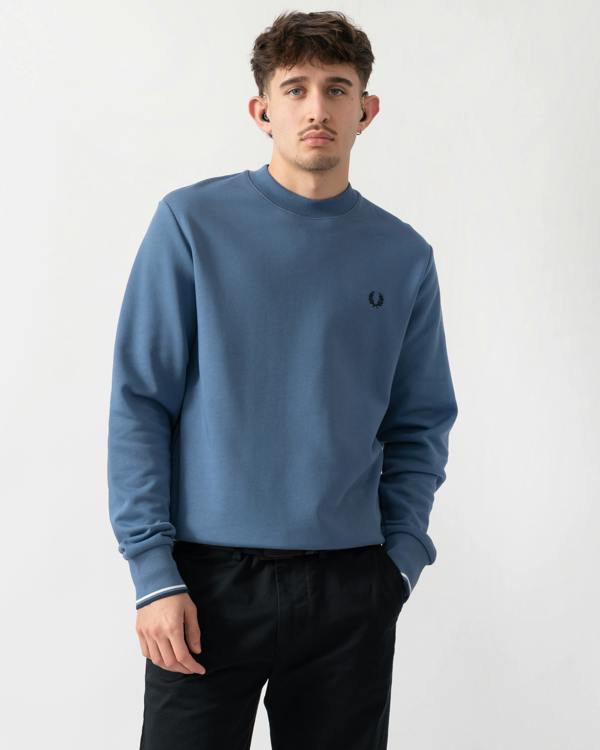 studio shot of a model wearing a Fred Perry Mens Crew Neck Sweatshirt in Ace Blue with Snow White & Tennis Blue trim