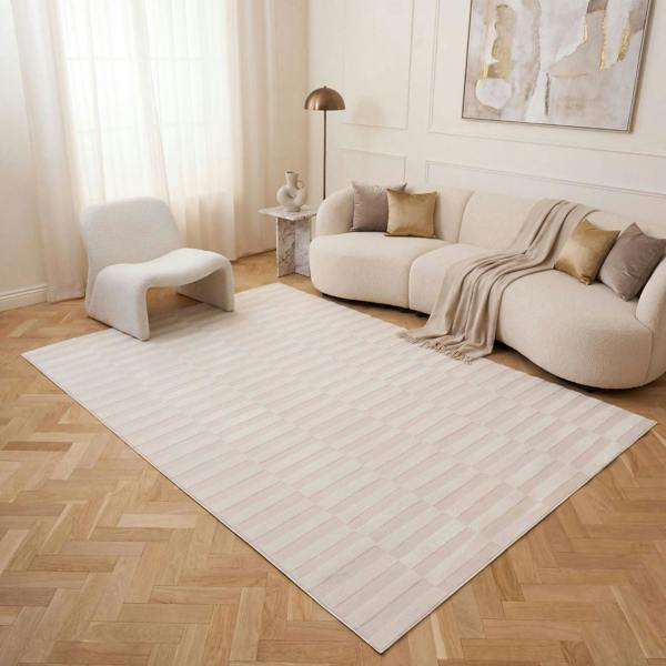 Modern living room with a white rug, beige sofa, and decorative elements.