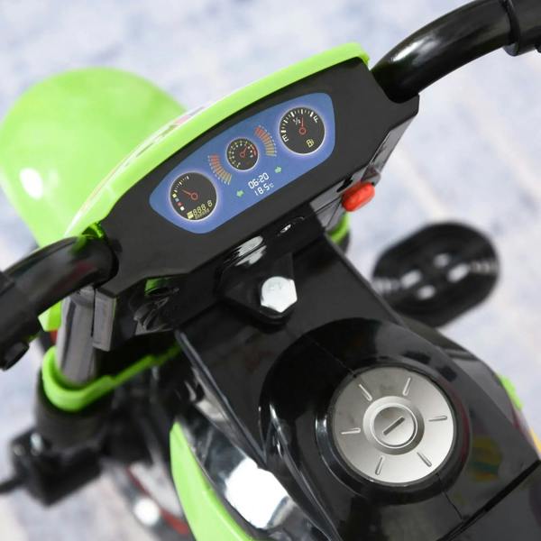 Close-up of green kids ride-on motorcycle trike dashboard with gauges and round ignition knob.