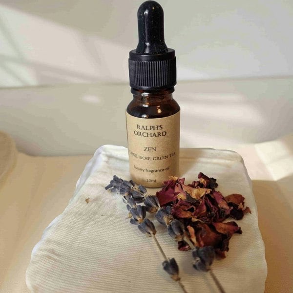 Bottle of Ralph's Orchard Zen fragrance oil with dried flowers on a white surface