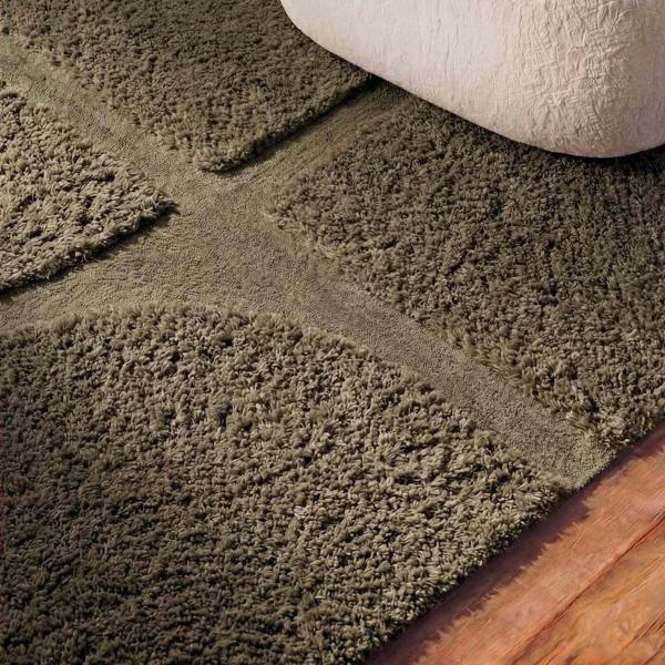 Close-up of a textured brown carpet with a wooden floor.