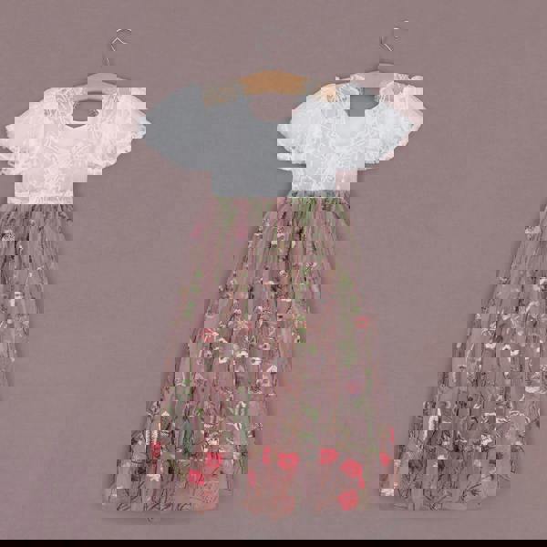 Children's dress with floral pattern on a hanger against a brown background