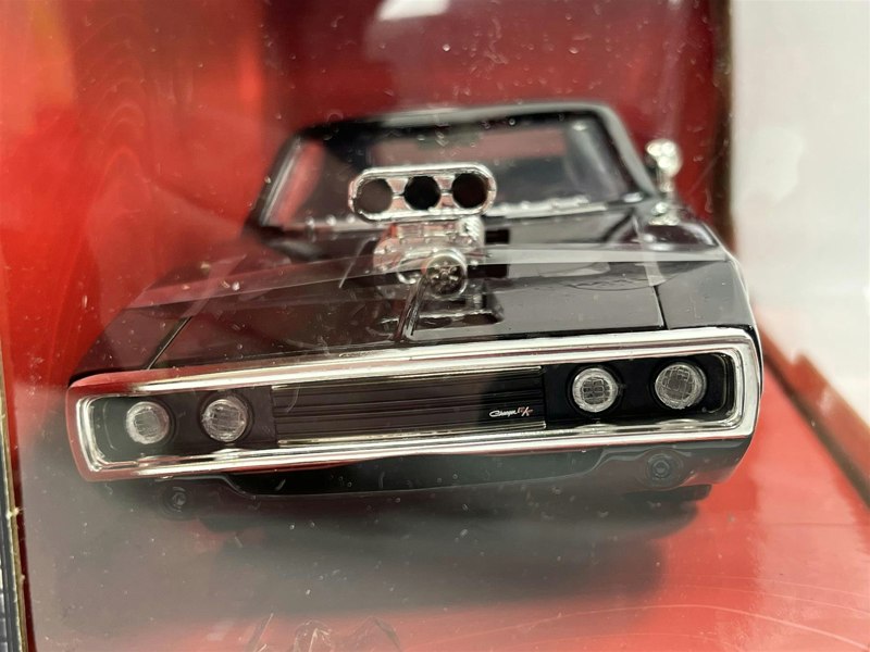 a black toy car in a glass case