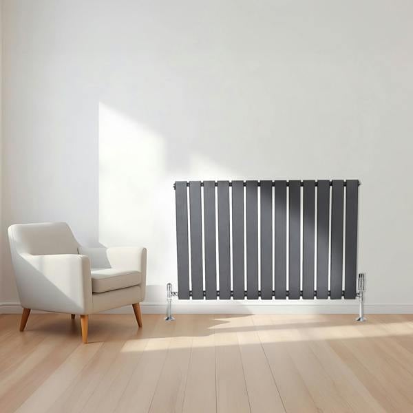 Flat single column radiator in anthracite grey, featuring sleek vertical panels, positioned beside a modern white armchair in a bright room