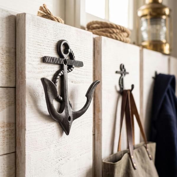 Close-up of anchor-shaped double coat hook mounted on textured white-washed wooden wall, showcasing sleek black finish and sturdy design.