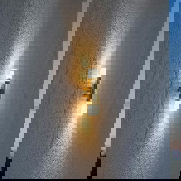 brass up and down exterior light mounted on a textured exterior wall 