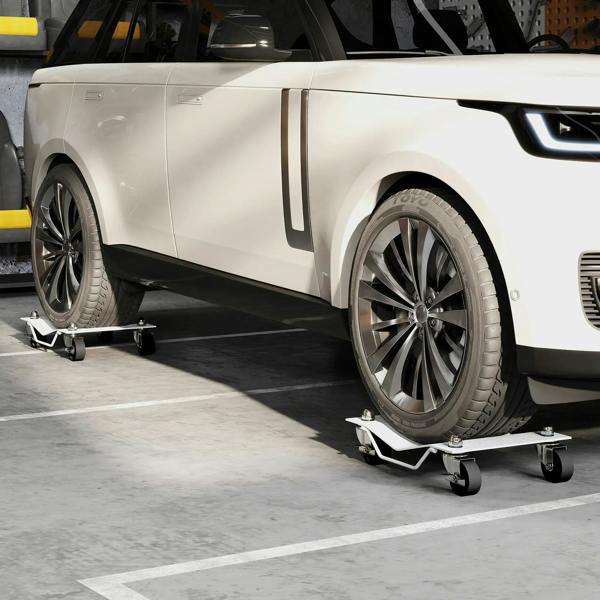 Metal wheel dolly with swivel casters under a car tire in a workshop.