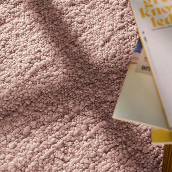 Close-up of a textured pink fabric with a product partially visible.