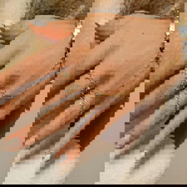 Hand wearing gold rings and a bracelet with a neutral background. Lifestyle-image of a woman-wearing the Enchanting-Flutterfly-sterling-silver-ring. The-photo demonstrates the-dainty-stackable-silhouette, showing how the-butterfly-motif sits elegantly on the-finger. Styled-for-effortless-beauty, this-image illustrates the-ring's-proportions for solo-wear or layering, making it an-ideal-example of everyday-luxury-wear and a-sentimental-gift-for-her