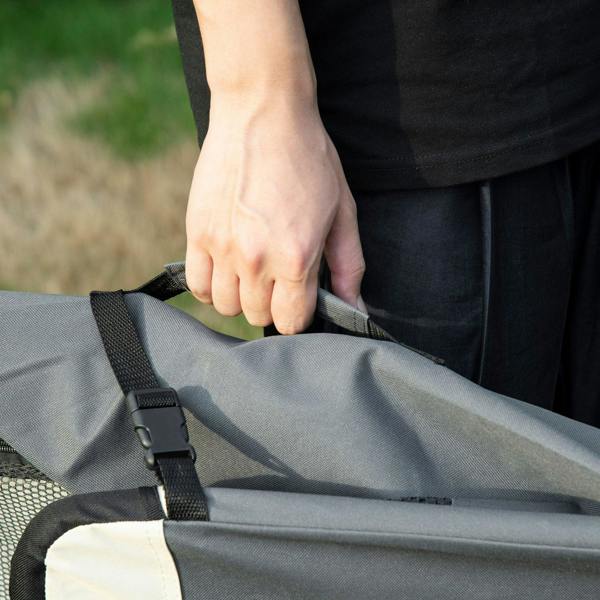 Grey pet carrier with carry strap and mesh panel, opened and held by a hand