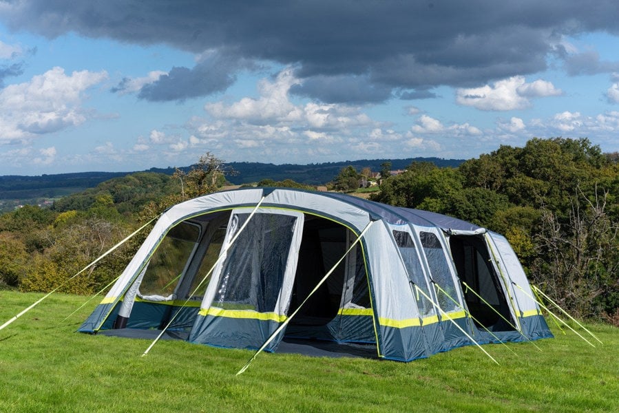 The OLPRO Odyssey  Breeze® Inflatable 8 Berth Tent pitched in a campsite with a treeline in the background.