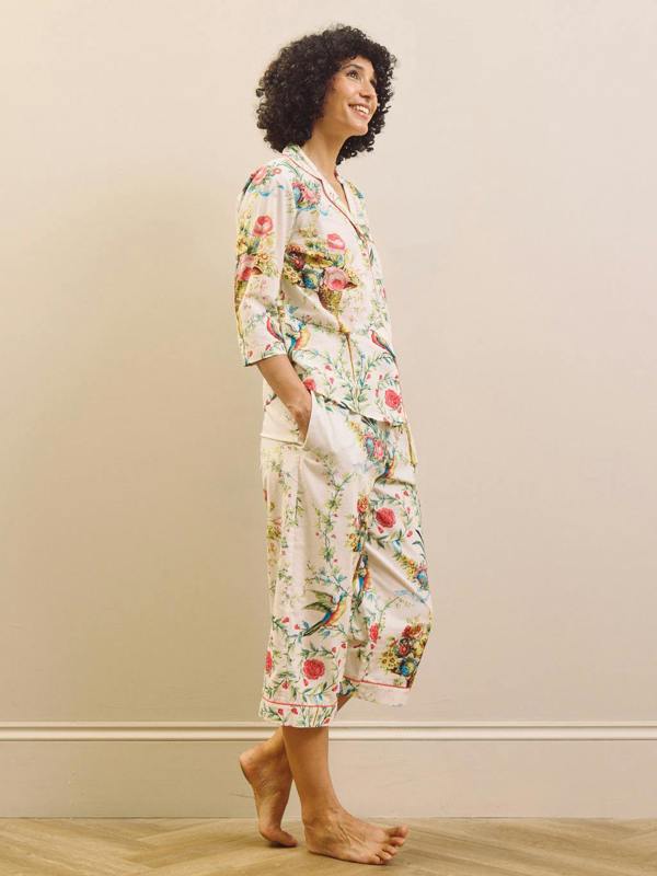 Woman wearing a floral capri pyjama set against a plain background