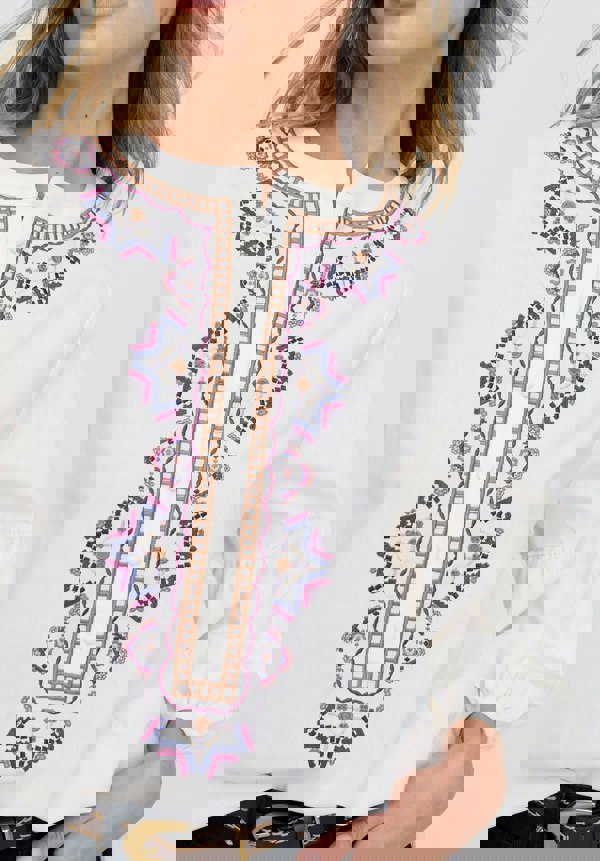White blouse with intricate embroidery details on a white background