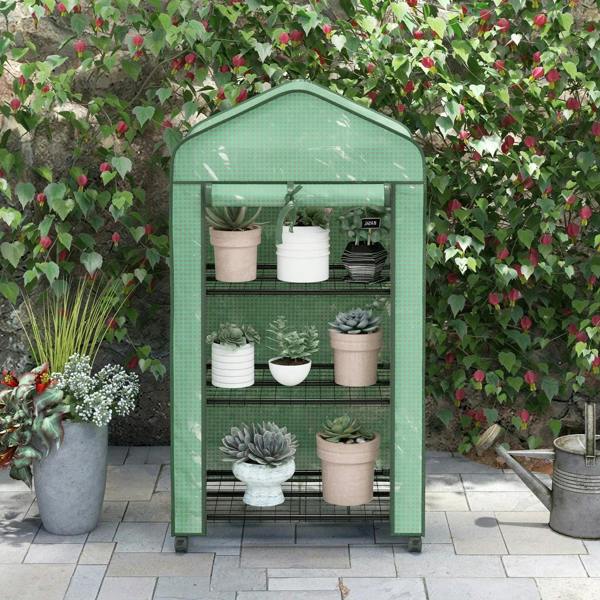 Green three-tier mini greenhouse with black wire shelves holding potted plants