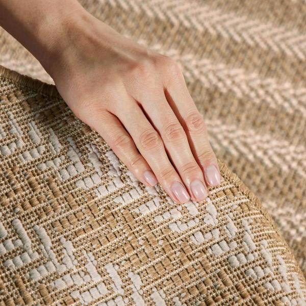 Hand with light pink nail polish resting on a textured woven surface