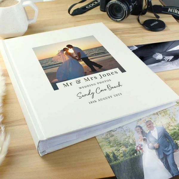 A white square wedding photo album with a cover photo of a bride and groom kissing on a beach, custom printed with 'Mr & Mrs Jones'.