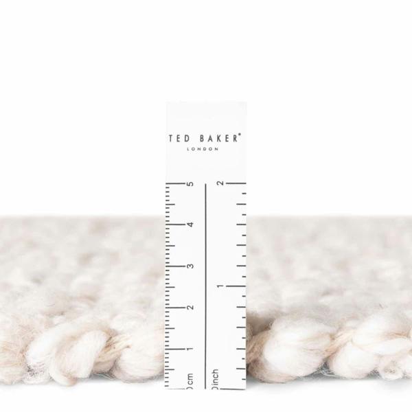 Close-up of white yarn with a ruler and 'Ted Baker London' branding.