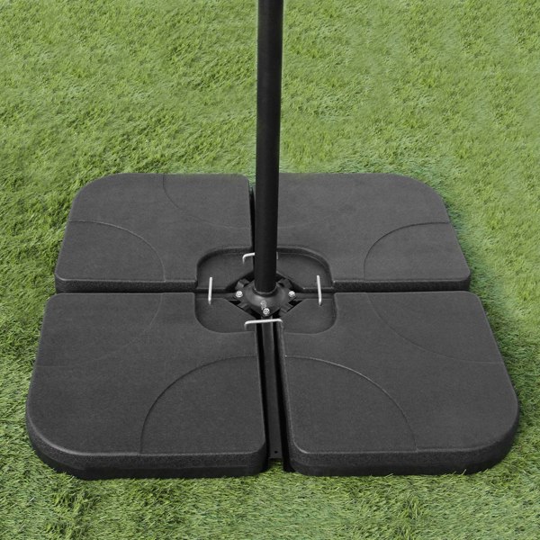 Black parasol base with four interlocking sections, designed for stability, set on green grass background for outdoor use
