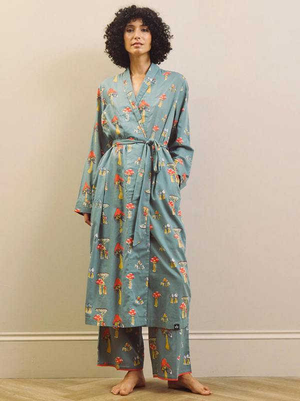 Woman wearing a greymushroom patterned robe against a beige wall.