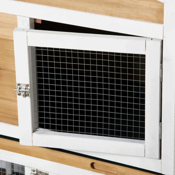 Close-up of wire mesh door on white rabbit hutch with side hinge and latch hardware