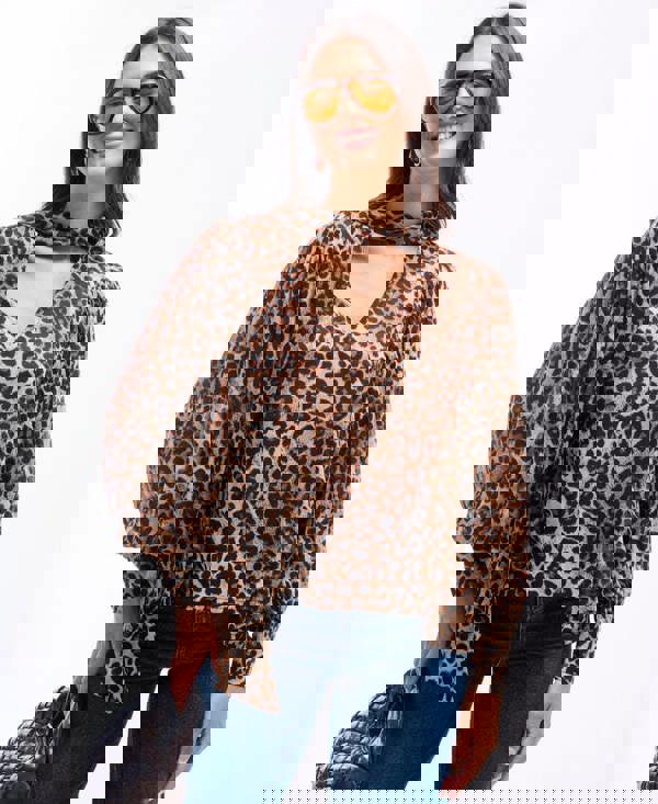 Woman wearing a leopard print blouse and sunglasses on a white background