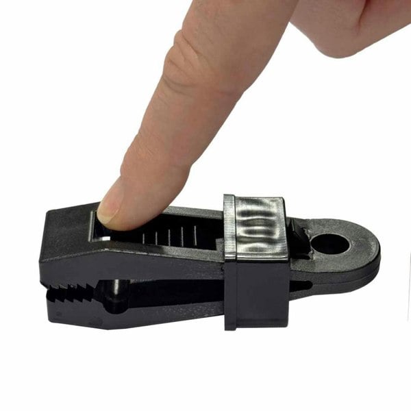 An image depicting a finger pressing the OLPRO Tent Groundsheet Pegging Clamp to demonstrate how to loosen the grip. Available in a pack of four.