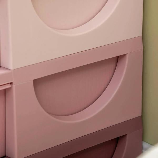 Close-up of pink front drawer bins with curved cutout handles and molded edges