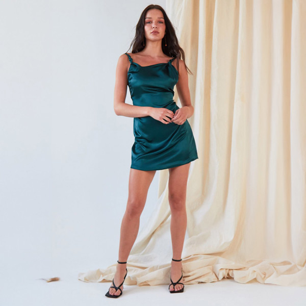 The model is wearing a Sarvin Green Backless Mini Dress.