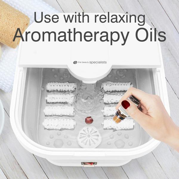 A hand pouring aromatherapy oils into the Foldaway Foot Spa Bath to enhance relaxation. The text promotes the use of "Aromatherapy Oils," making this foot spa machine one of the best foot spa options for combining massage, heat, and aromatherapy in a foot soaker.
