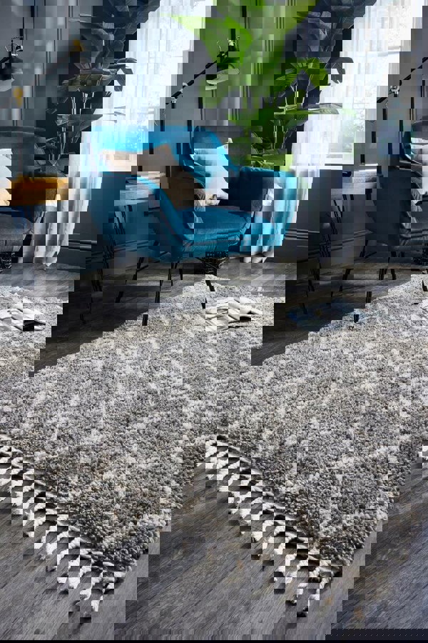 Moroccan-style shag rug in grey with white pattern, paired with a blue armchair in a stylish living room setting.