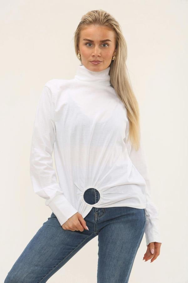 Woman wearing a white turtleneck sweater and blue jeans on a plain background