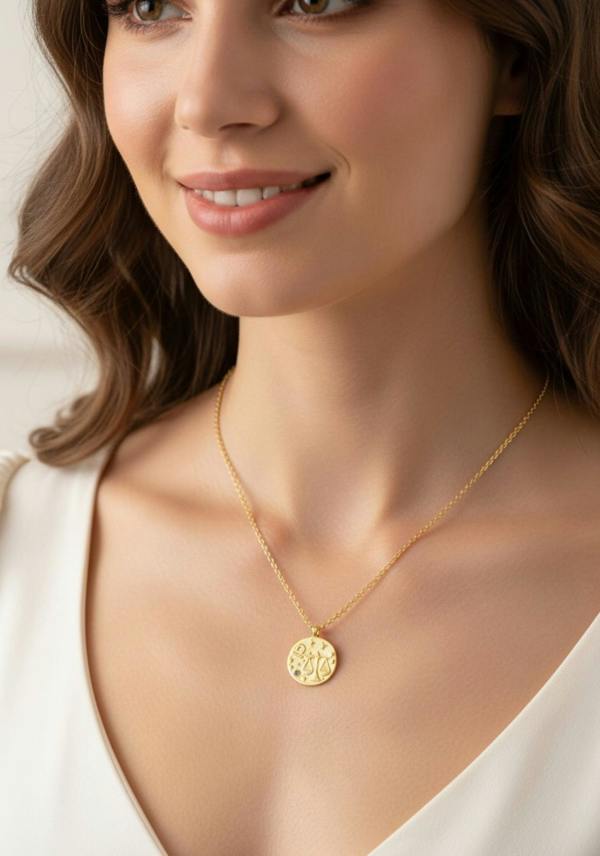 Woman wearing a gold necklace with a circular pendant on a neutral background