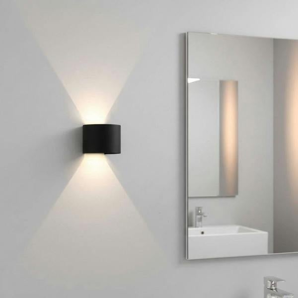 black bathroom wall sconce mounted on the wall in a modern bathroom next to the mirror 
