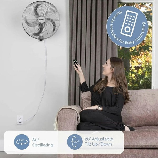 A photo of a woman using the optional remote control to control her Senelux chrome wall mounted fan