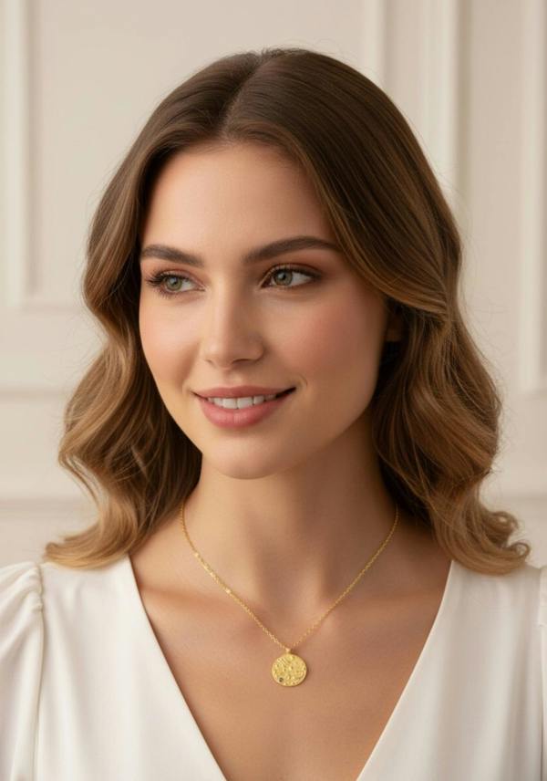 Woman wearing a gold necklace with a pendant against a neutral background