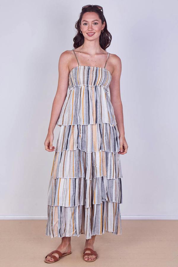 Woman wearing a striped tiered dress against a plain background