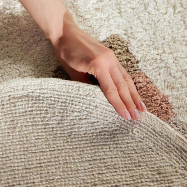 Hand touching a textured beige carpet