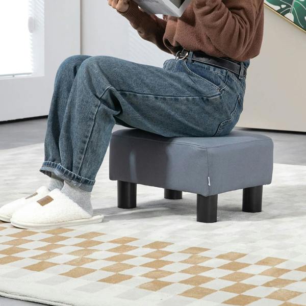 Grey footstool used as a footrest with padded seat and dark legs