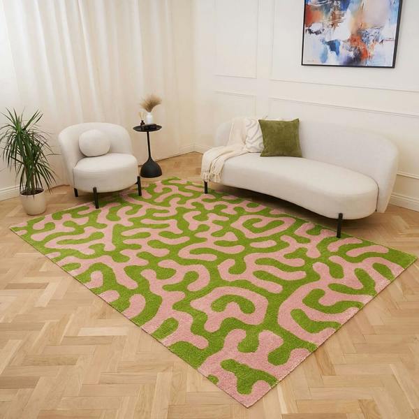 Living room with a green and pink patterned rug, white sofa, and abstract painting on the wall.