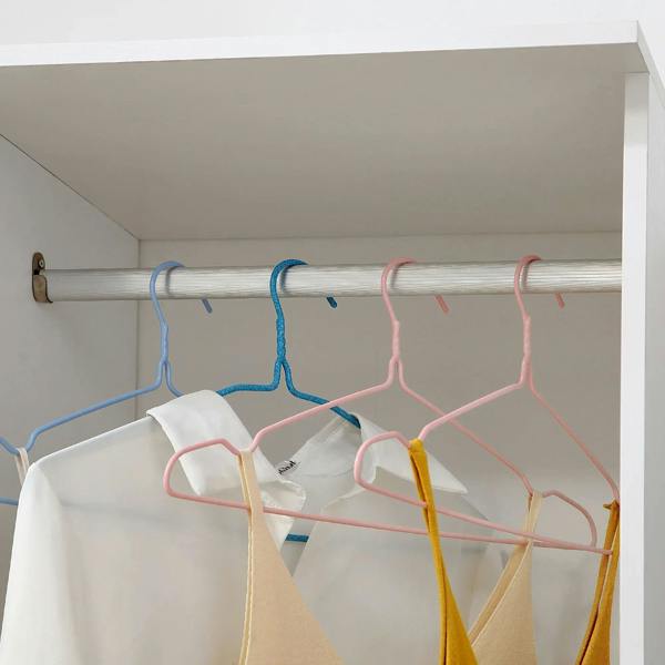 Close-up of hanging rail with colorful hangers inside a white wardrobe