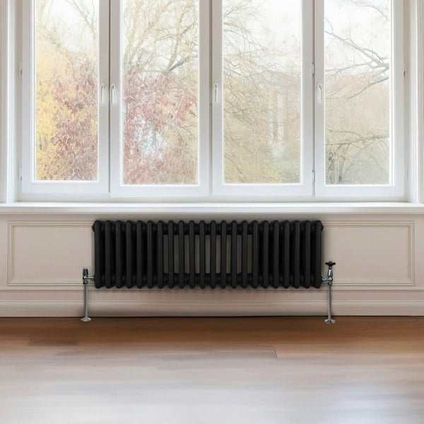 Traditional black 3 column radiator, 300 x 1012mm, featuring a sleek design with a smooth finish, positioned beneath large windows